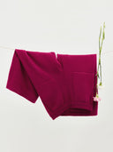 Dzianinowe spodnie w kolorze magenty zawieszone na sznurku z kwiatami