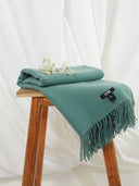 Złożony turkusowy szal na drewnianym stołku z białymi kwiatami