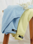 Niebieski i jasnozielony sweter na drewnianym krześle